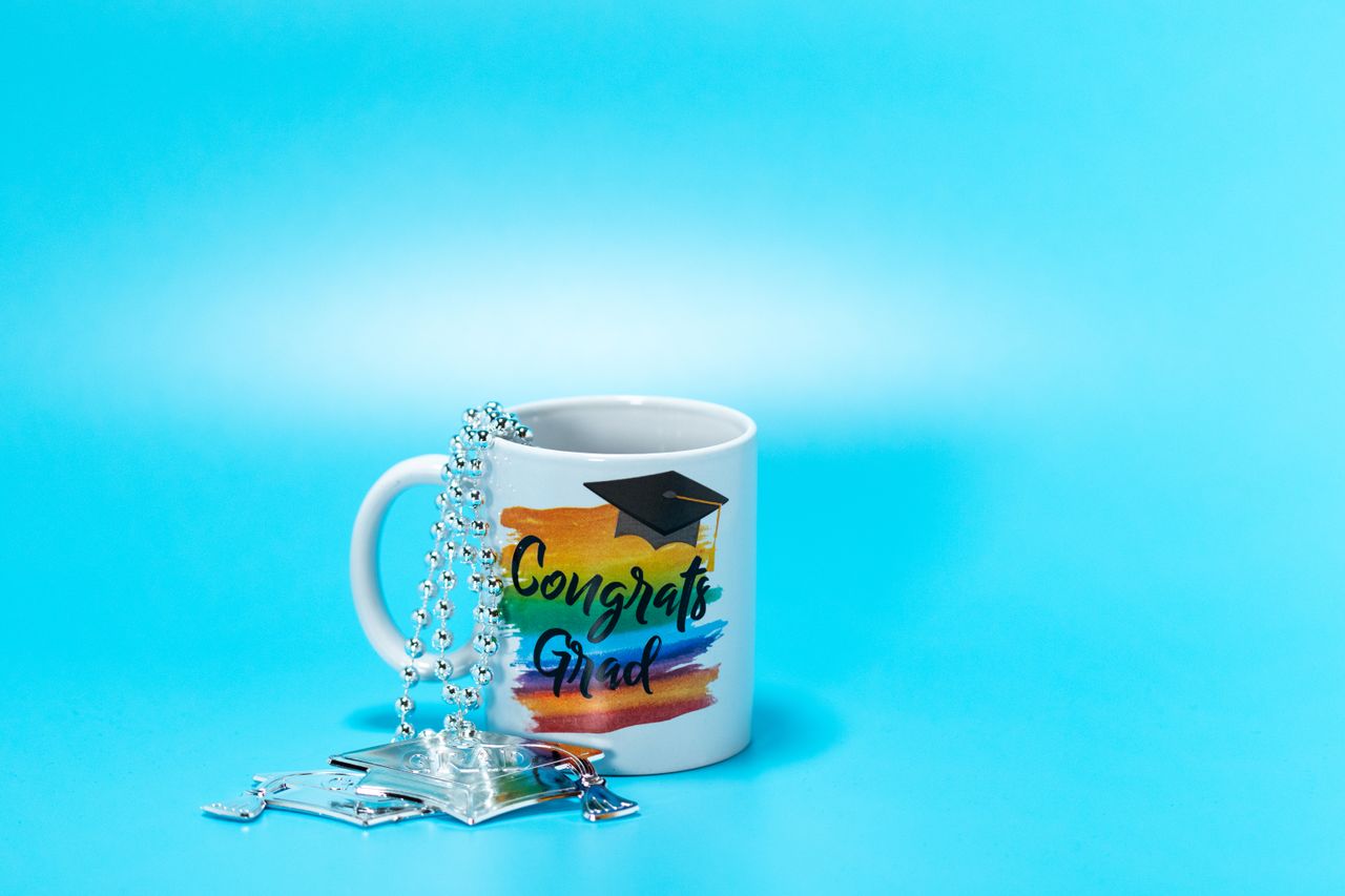 contact-img Colorful mug with graduation cap decoration on a light blue backdrop, perfect for celebration themes.